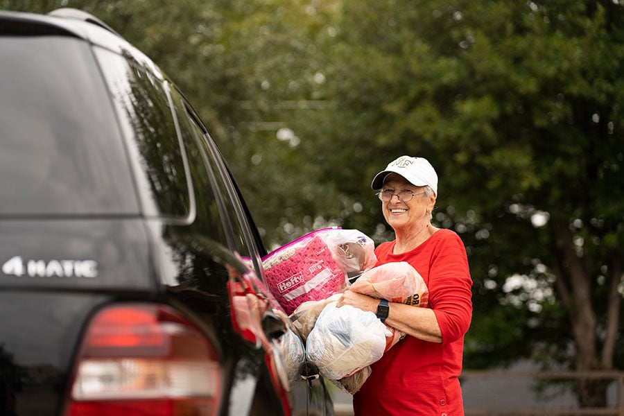 a volunteer hands supplies to a car